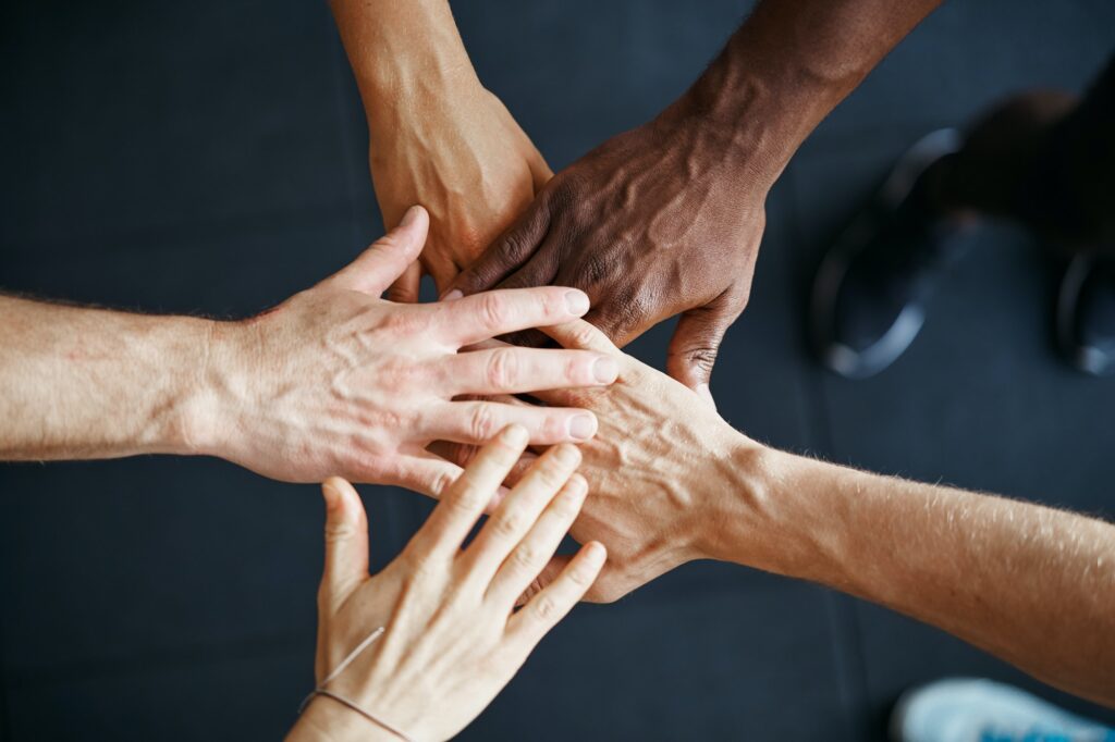 Diverse people standing with their hands together in a gym